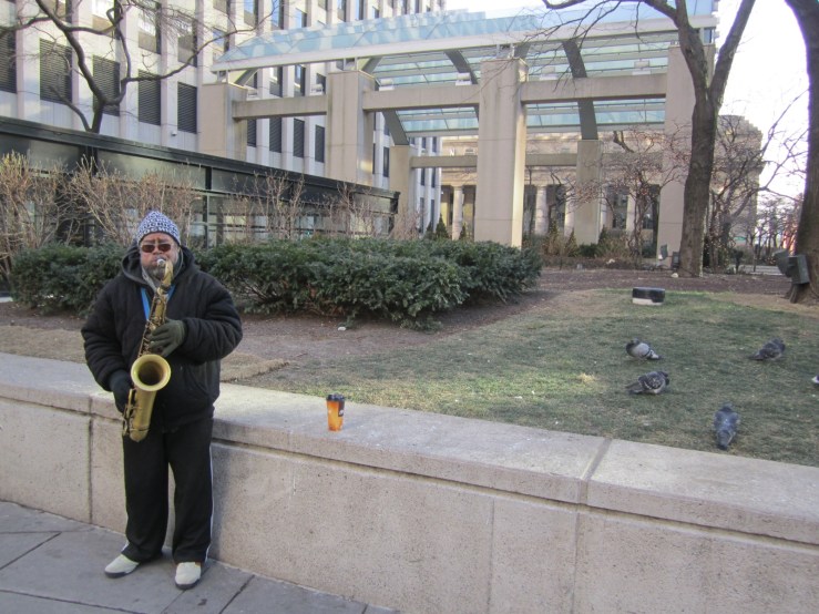This guy is actually playing to a group of people braving the cold for a smoke break, but I liked the shot with the pigeons most.